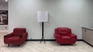 Une pièce avec deux chaises rouges, un lampadaire et un tableau accroché au mur.
