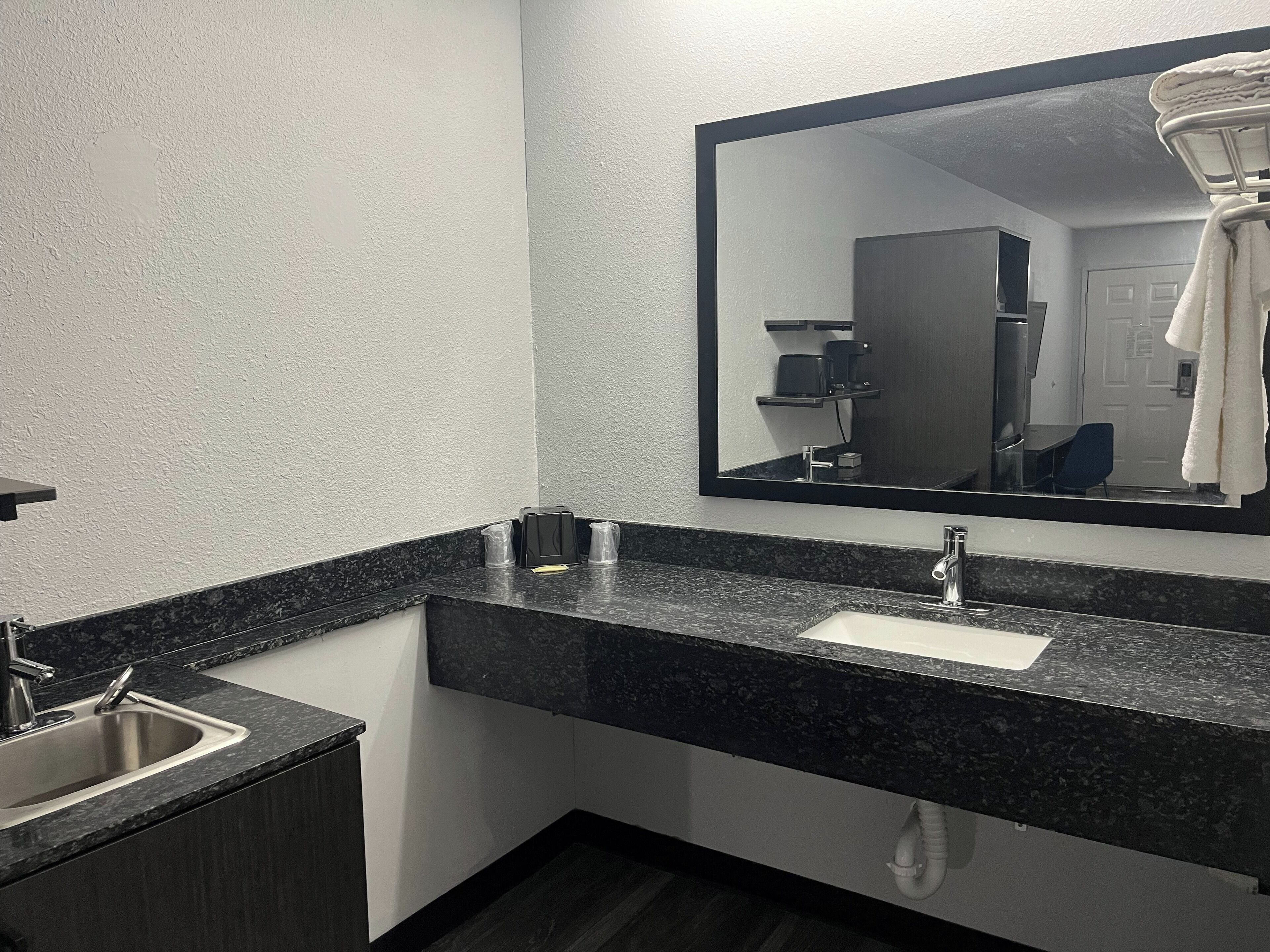 Ein modernes Badezimmer mit einer Granitplatte, einem Waschbecken und einem großen Spiegel.