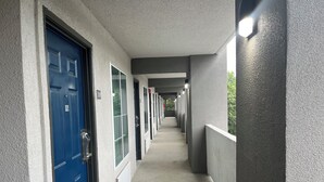 Un couloir bordé de portes, chacune étant numérotée, qui donnent accès à des pièces individuelles.