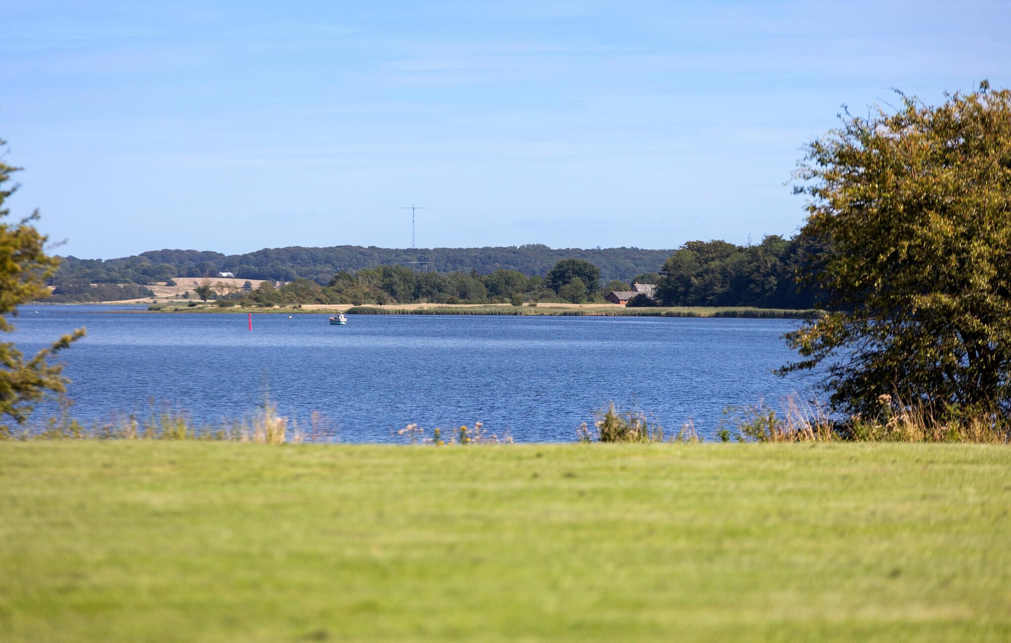 Un lago con un bote, rodeado de zonas verdes y árboles.