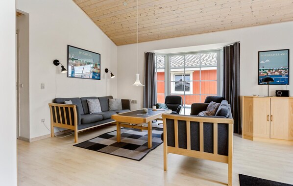 A modern living room with a sofa, chairs, a coffee table, and artwork on the walls.
