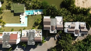 Vista aérea de una zona residencial con varias casas, una piscina y una playa.