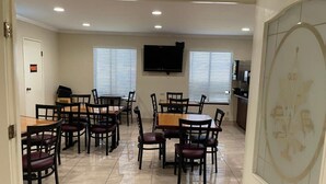 Comedor con varias mesas y sillas, un televisor de pantalla plana montado en la pared y una puerta con la etiqueta 'PRIVATE'.