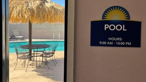 Zona de piscina con un letrero que indica el horario de apertura y cierre de la piscina, de 9:00 a 22:00.