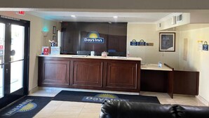 Zona de recepción con cartel de Days Inn, mostrador de recepción y sofá de cuero.