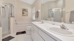 A modern bathroom with a walk-in shower, a bathtub, a toilet, and a double sink vanity. - Deer Run in Wesley Chapel 4br-3ba (Zephyrhills)