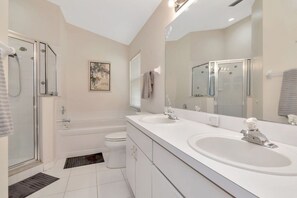 A modern bathroom with a walk-in shower, a bathtub, a toilet, and a double sink vanity.
