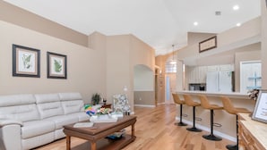 A living room with a beige sofa, a wooden coffee table, and framed botanical prints on the wall. - Deer Run in Wesley Chapel 4br-3ba (Zephyrhills)