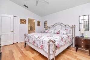 A bedroom with a bed, a nightstand, a door, and a ceiling fan.