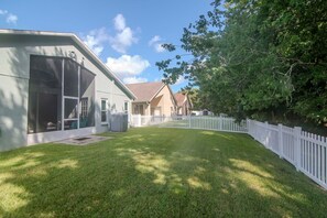 A residential property with a fenced backyard, a screened porch, and a well-maintained lawn. - Deer Run in Wesley Chapel 4br-3ba (Zephyrhills)