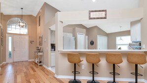 A kitchen with a bar area, wooden flooring, and a pendant light. - Deer Run in Wesley Chapel 4br-3ba (Zephyrhills)
