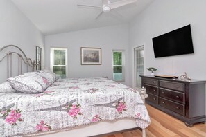 Une chambre à coucher avec un lit, une commode et un téléviseur à écran plat fixé au mur.