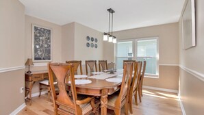 A dining room with a wooden table and chairs, a chandelier, a window, and wall decorations. - Deer Run in Wesley Chapel 4br-3ba (Zephyrhills)