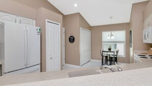 A modern kitchen with white appliances, a dining area with a table and chairs, and a pendant light. - Deer Run in Wesley Chapel 4br-3ba (Zephyrhills)
