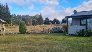 A rural property with a wooden playhouse, a small shed, and a house with a satellite dish.