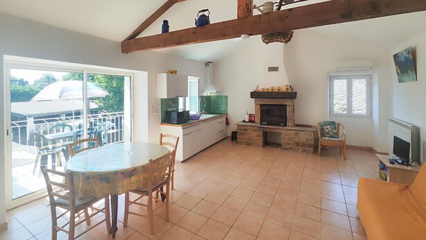 Amplia sala de estar con mesa de comedor, sillas, chimenea y vista al exterior.