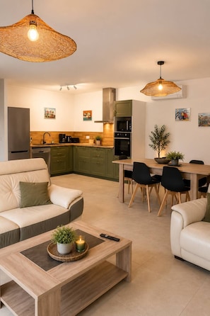 A modern kitchen with a dining area, including a sofa, coffee table, and pendant lights.