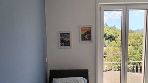 A bedroom with a bed, a window, and two framed pictures on the wall. - Family apartment near Salerno, the Amalfi and Cilento coasts. (Baronissi)
