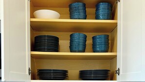Una cocina con un mueble de madera que contiene platos y tazones apilados.