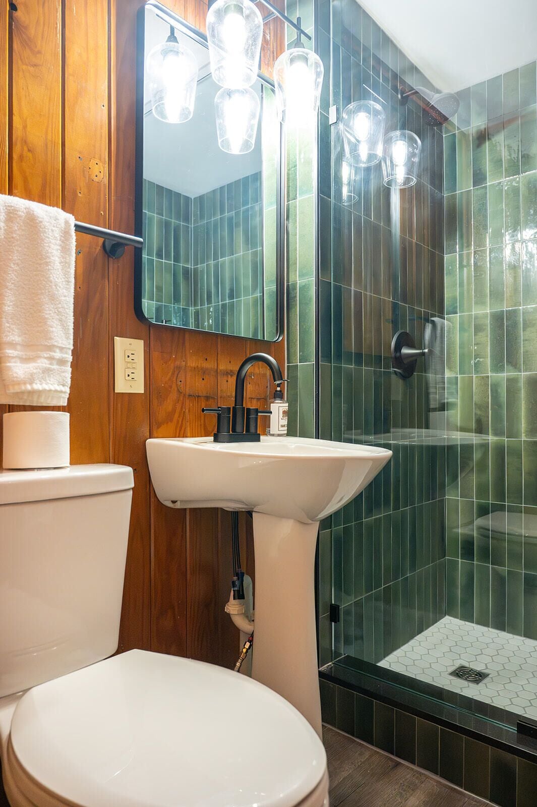 A bathroom with a toilet, sink, mirror, and shower.