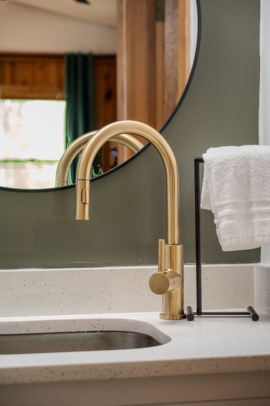 Ein Badezimmer mit goldenem Wasserhahn, Waschbecken und Spiegel.