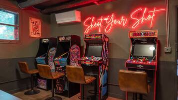 A retro arcade with neon signage, vintage arcade machines, and leather bar stools.
