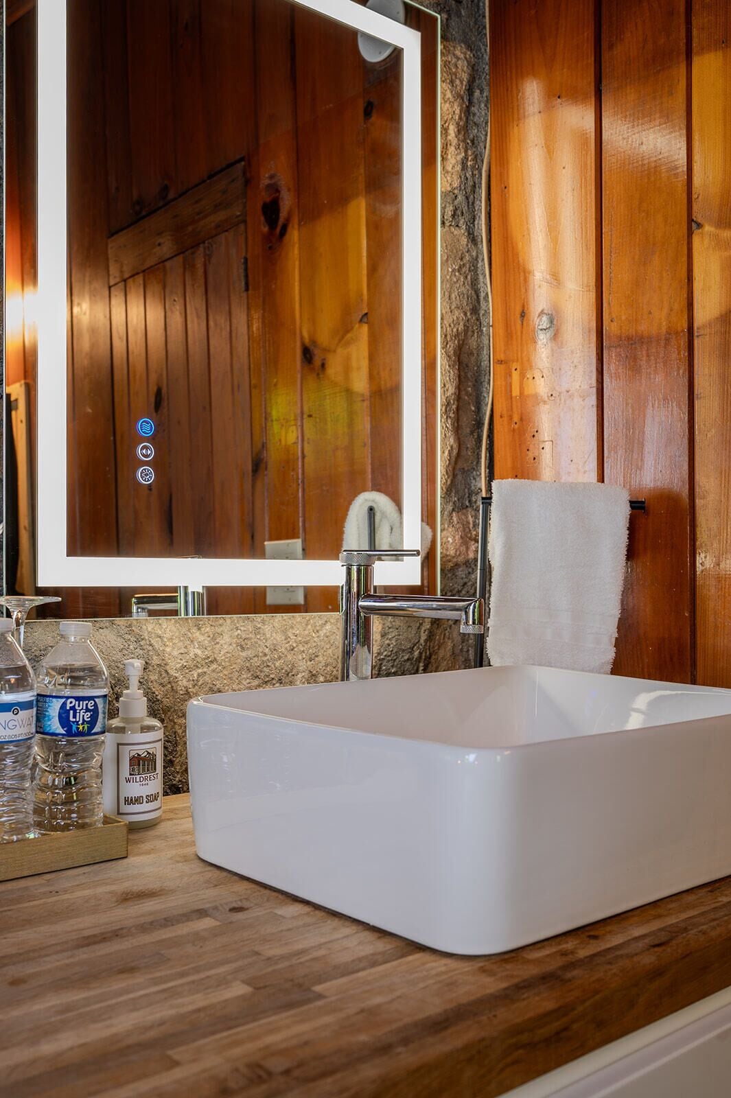 A bathroom with a white sink, a mirror, and wooden walls.