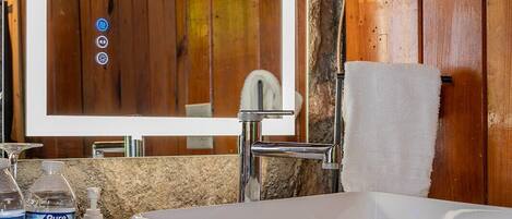 A bathroom with a white sink, a mirror, and wooden walls.