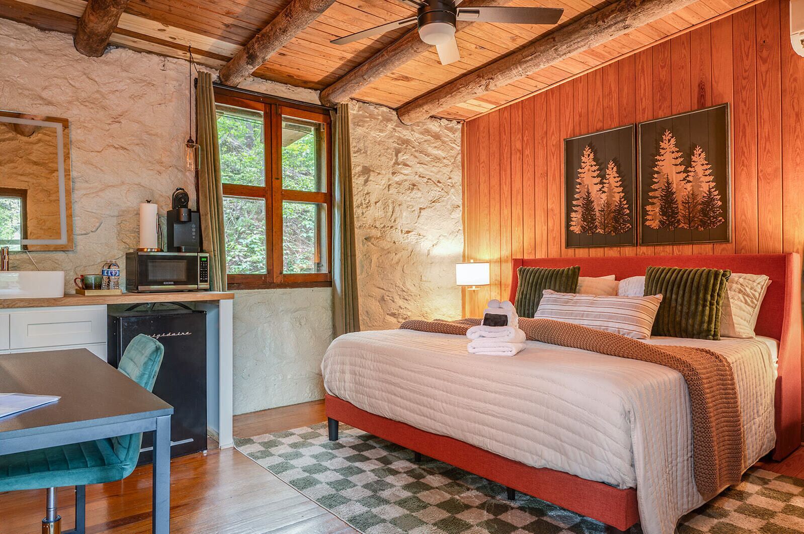 Una habitación acogedora con cama, escritorio, microondas y ventana con cortinas.