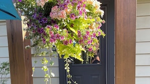 A porch with a hanging flower arrangement and a potted plant. - Snowbird Delight (Victoria)