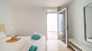 A modern hotel room with a large bed, a nightstand, a wardrobe, and a view of the outside. - Casa Apolo (Puerto del Carmen)