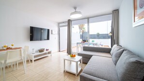 A modern living room with a grey sofa, a white coffee table, and a TV mounted on the wall. - Casa Apolo (Puerto del Carmen)