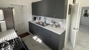 Una cucina moderna con mobili antracite, un piano di lavoro bianco e un lavello in acciaio inossidabile.