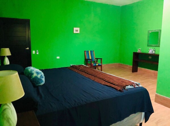 A room with a bed, a chair, a desk, and a lamp.