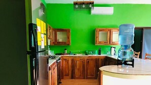 Une cuisine avec des armoires en bois, un réfrigérateur, un distributeur d’eau et une cuisinière.