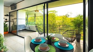 Un balcón con una mesa dispuesta para cuatro personas, sillas y plantas en macetas.