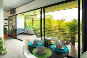 Een balkon met een tafel voor vier personen, stoelen en potplanten.