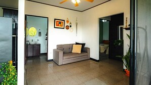 Una sala de estar moderna con un ventilador de techo, un sofá y un comedor al fondo.