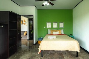 A bedroom with a bed, a ceiling fan, and a green wall.