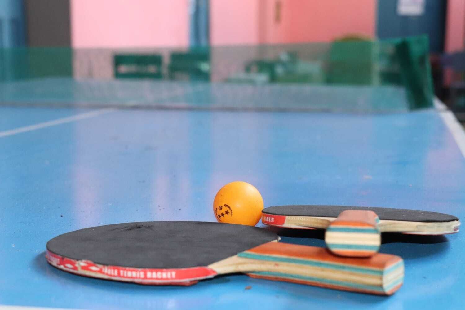 Et bordtennisbord med to bat og en bold.