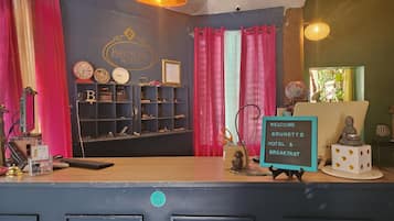 Zona de recepción de un hotel con un letrero que dice "Welcome to Brunette Hotel & Breakfast".