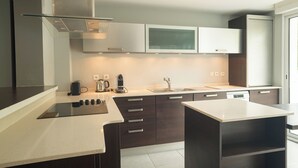 Una cocina moderna con una isla central, armarios oscuros y una ventana con persianas.