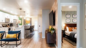 A modern apartment with a kitchen, dining area, and a bedroom.
