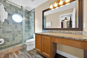 A modern bathroom with a glass shower enclosure, a white toilet, and a vanity with a granite countertop. - Free Pool Heat! Luxury Oasis | Pool, Spa & Sunset Views by Disney (Kissimmee)