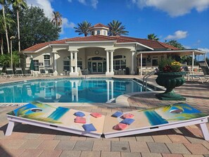A pool with lounge chairs and a building with a red-tiled roof. - Free Pool Heat! Luxury Oasis | Pool, Spa & Sunset Views by Disney (Kissimmee)