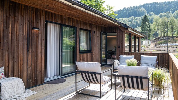 A wooden deck with outdoor seating and a view of a forested hillside.