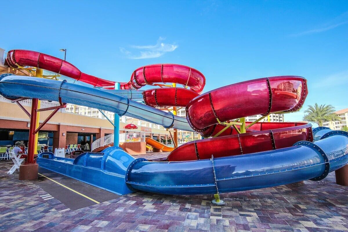 Un parc aquàtic amb diverses tobogans d'aigua vermells i blaus.