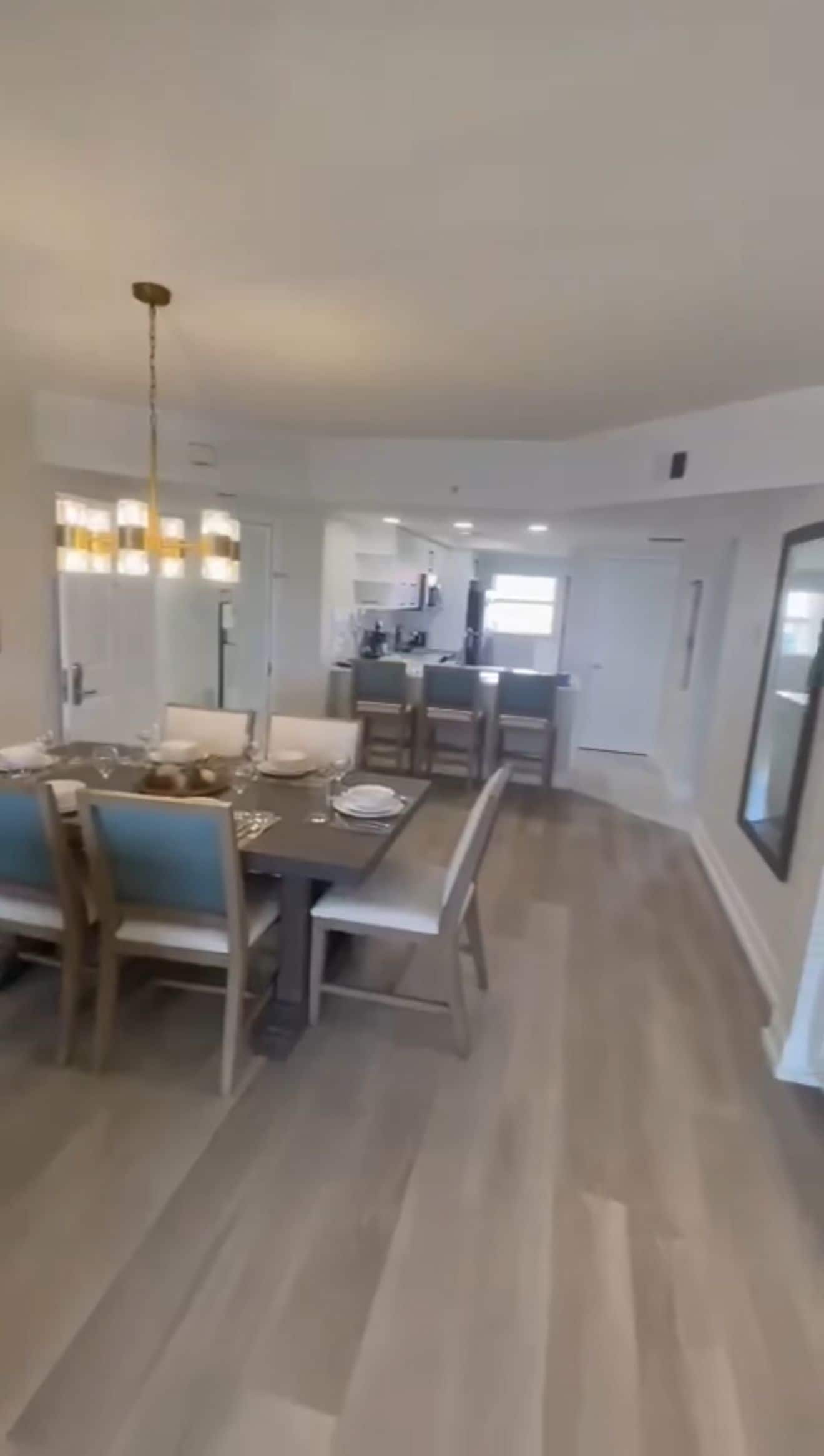A spacious dining area with a long table, chairs, and a chandelier.