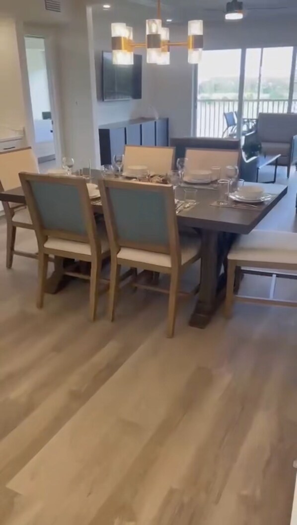 A dining area with a wooden table set for four, surrounded by chairs.