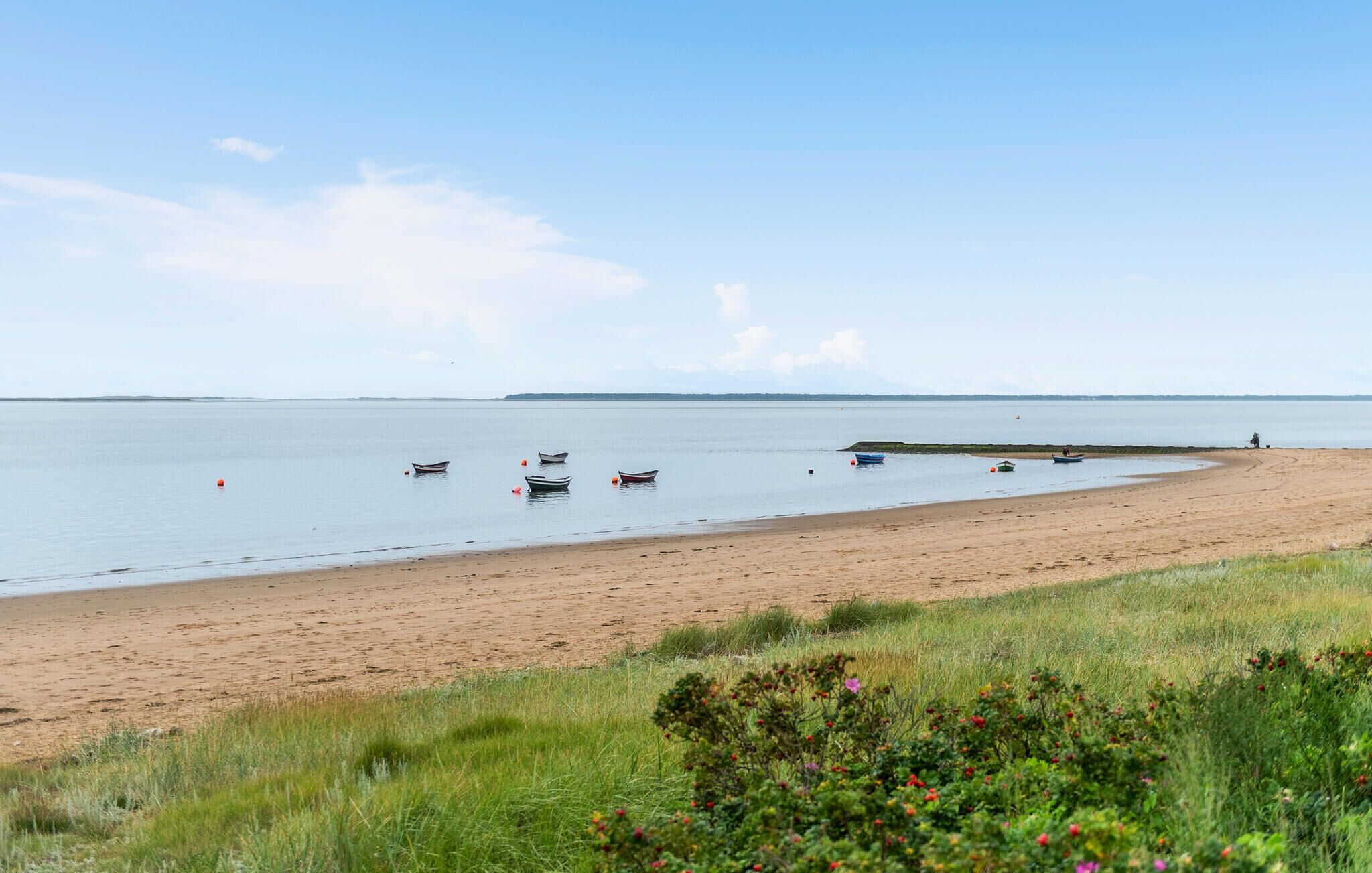 A sandy beach with several small boats anchored in the water.